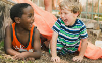 two children laughing in an outdoor classroom